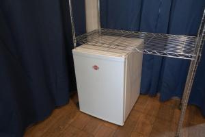 a small white refrigerator in a room with blue curtains at Yguazú Resort - Cabañas & Camping in Juan E. Oʼleary