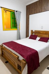 a bedroom with a large wooden bed with red pillows at HotelSueño Dorado Aguadas in Aguadas