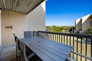 a wooden deck with a table and chairs on a balcony at QCB5 - Saltaire Sunrise in Nags Head