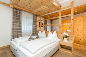 ein Schlafzimmer mit einem großen weißen Bett in einem Zimmer mit Holzwänden in der Unterkunft Hotel Bel Sit in Kurfar