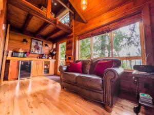 a living room with a leather couch in a cabin at Owl's Perch Treehouse in Sooke