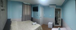 a small bedroom with a bed and a blue wall at Pousada Hotel Sol Nascente in Mafra