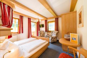 a bedroom with a bed and a desk in a room at Hotel Landhaus Marchfeld in Oberau