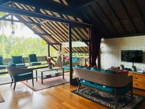 a living room with blue chairs and a tv at The Papas Villas in Tegalalang