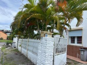 a white fence with a gate and a palm tree at La maison de la plage in Sainte-Luce