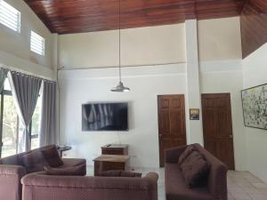 a living room with two couches and a tv at Casa Maria in Sibulan