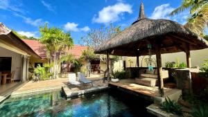 a house with a swimming pool with a thatch roof at Searenity Villa in Grand-Baie