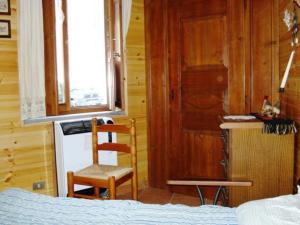 a bedroom with a bed and a chair and a window at Appartamento Bianco in Borgata Sestriere