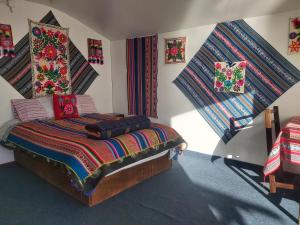 a bedroom with a bed with colorful blankets and pillows at Uros & Titicaca Sunset Comfort Floating cabins in Puno