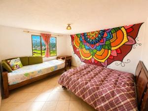 a bedroom with a bed and a large painting on the wall at Hostal Casa Lantana in Suesca