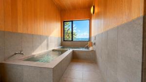 a bathroom with a large tub with a window at Private Villa 蒼 Lala & Lino in Kyotango