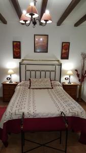 カベズエラデルバレにあるApartamentos Rurales Tauroのベッドルーム1室(大型ベッド1台、テーブル2台、ランプ2つ付)