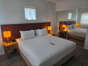 a bedroom with a large white bed and two lamps at Quest Palmerston - Darwin in Palmerston +27 photos