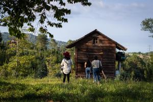 Drei Personen stehen vor einer kleinen Holzhütte in der Unterkunft Bosque de Niebla in Tlatlauquitepec