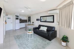 a living room with a black couch and a kitchen at Central Mooloolaba Beachfront Apartment - Located in Sandcastles Resort in Mooloolaba
