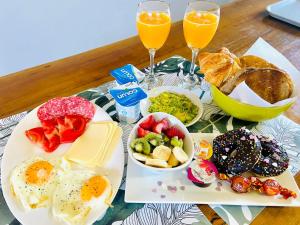 a table with a plate of breakfast food and two glasses of orange juice at Mini Regugio in Chillán