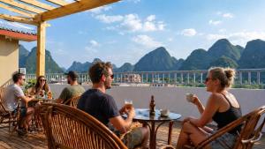 a group of people sitting at a table on a deck at Yangshuo Eden's Social Guesthouse - cozy garden courtyard & fresh craft coffee & night beers & outdoor activities in Yangshuo