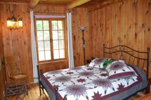 um quarto com uma cama num quarto com paredes de madeira em Aux Retrouvailles em Lac-Mégantic