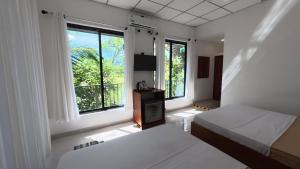 a white room with two beds and a window at Sewana Cottage in Kurunegala