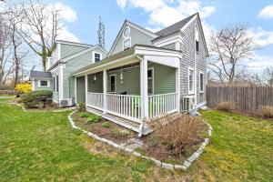 a green house with a white porch on a yard at 3 Bedroom Cape House by Leavetown Vacations in Sandwich