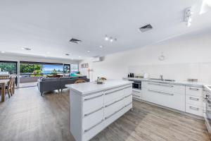 a kitchen with white cabinets and a living room at Blue Lagoon Airlie Beach in Airlie Beach