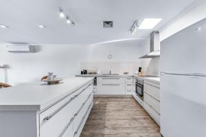 a white kitchen with white appliances and wooden floors at Blue Lagoon Airlie Beach in Airlie Beach +36 photos