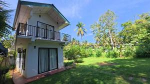 a house with a balcony and a yard at Sewana Cottage in Kurunegala