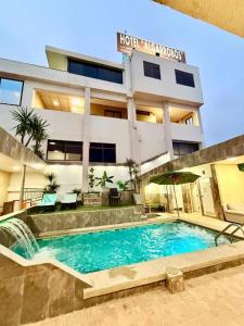 a hotel with a swimming pool in front of a building at Hotel Los Algarrobos in Puerto Baquerizo Moreno