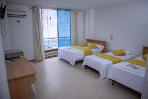 a hotel room with three beds and a window at Hotel BENNY Los Leones Melgar in Melgar +12 photos