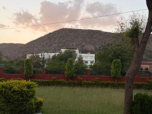 a mountain in the distance with a red fence at Sariska Haveli in Alwar