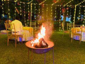 a fire pit in the yard with people sitting at tables at Sariska Haveli in Alwar