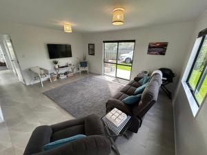 a living room with couches and a flat screen tv at Hosts on the Coast Make Memories on Cook in Whitianga