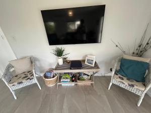 a living room with a table and two chairs and a tv at Hosts on the Coast Make Memories on Cook in Whitianga +18 photos