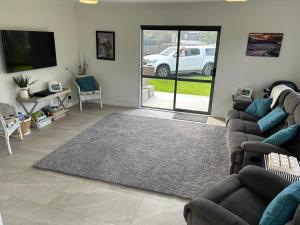 a living room with couches and a flat screen tv at Hosts on the Coast Make Memories on Cook in Whitianga