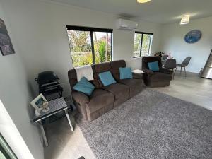 a living room with a brown couch and blue pillows at Hosts on the Coast Make Memories on Cook in Whitianga
