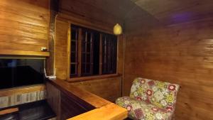 a living room with a chair and a television at Chalé dos ventos in Itamonte