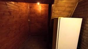 a refrigerator in a room with a wooden wall at Chalé dos ventos in Itamonte