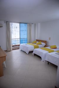 a room with three beds and a large window at Hotel BENNY Los Leones Melgar in Melgar