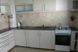 a kitchen with white cabinets and a stove and a sink at Mein Gästehaus in Gualeguaychú