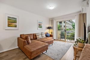 a living room with a brown couch and a window at Carrington Views - 3 Bedrooms - CBD - Parking in Adelaide