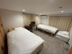a room with two beds and a desk with a computer at Tiz円居 in Minamiawaji