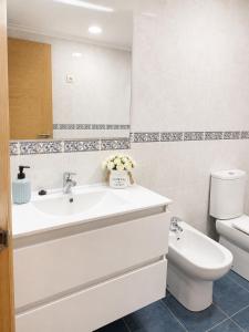 a white bathroom with a sink and a toilet at APARTAMENTO SOL in Viveiro