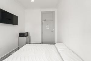 a white bedroom with a bed and a tv at Olympic Paddington Budget Hotel - across Allianz Stadium in Sydney
