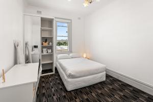 a white bedroom with a bed and a window at Olympic Paddington Budget Hotel - across Allianz Stadium in Sydney