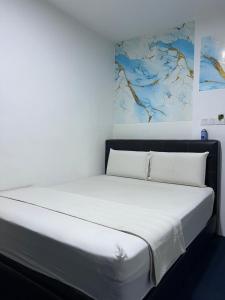 a bed in a room with a painting on the wall at Hotel Blue Orchid in Bayan Lepas