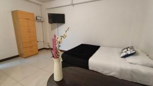 a bedroom with a bed and a vase with flowers on a table at Departamentos Céntricos en Lima in Lima