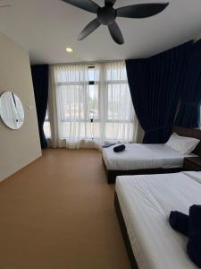 a hotel room with two beds and a ceiling fan at Tdoze Hotel At Piccadilly Ipoh in Ipoh