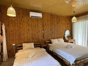 two beds in a room with wooden walls at Om Tara Retreat in Yên Bái