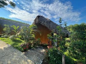a small hut with a thatched roof in a garden at Om Tara Retreat in Yên Bái