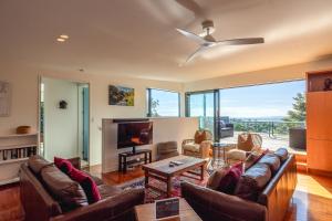 a living room with a couch and a tv and a fireplace at Hekerua Heights with Hot Tub and Seaviews in Oneroa